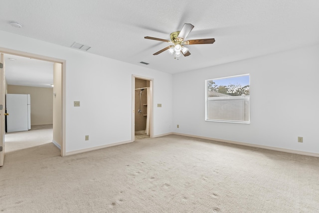 unfurnished bedroom featuring freestanding refrigerator, light colored carpet, visible vents, and baseboards