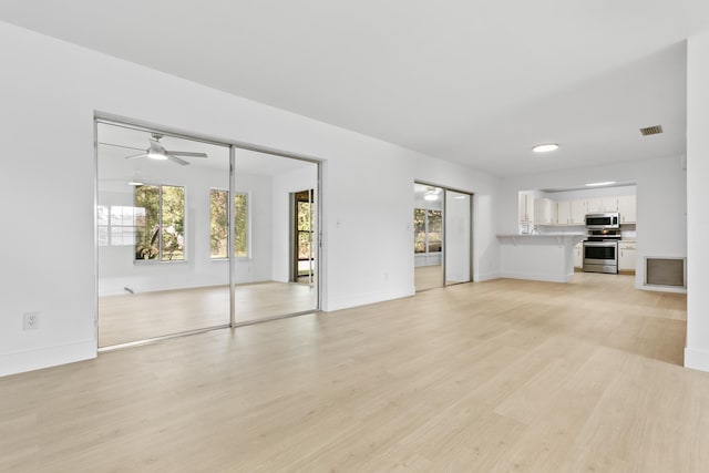 unfurnished living room with visible vents, a ceiling fan, light wood-style flooring, and baseboards