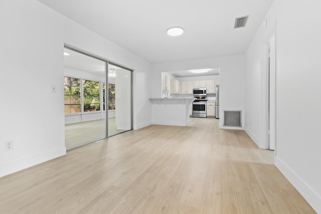 unfurnished living room with light wood finished floors, baseboards, and visible vents