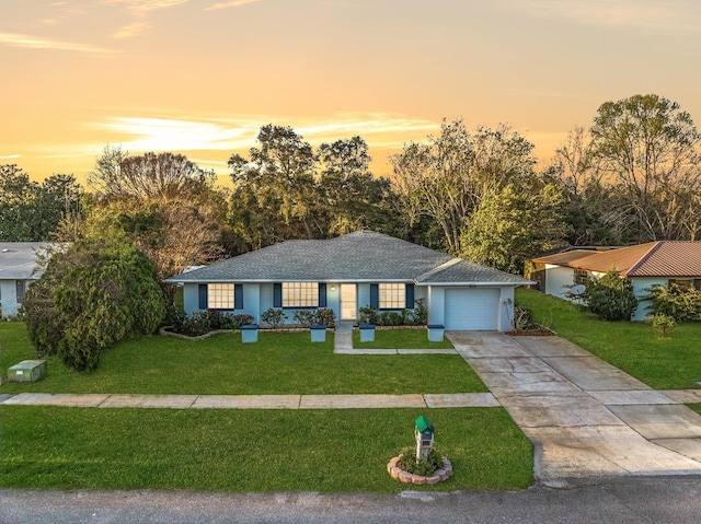 single story home with a garage, concrete driveway, a front yard, and roof with shingles