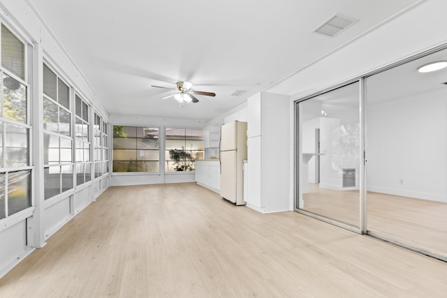 unfurnished sunroom with a wealth of natural light, visible vents, and a ceiling fan