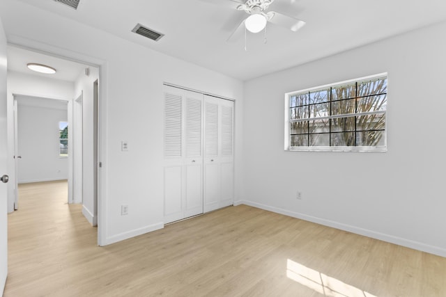 unfurnished bedroom featuring light wood finished floors, a closet, visible vents, and baseboards