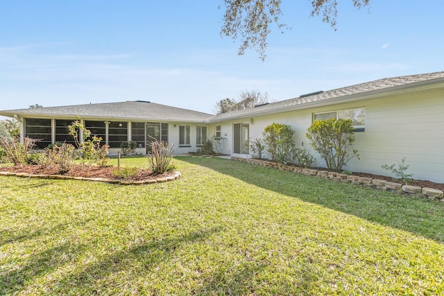 rear view of property featuring a lawn and a sunroom