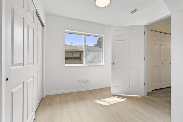 unfurnished bedroom with light wood finished floors, baseboards, and visible vents