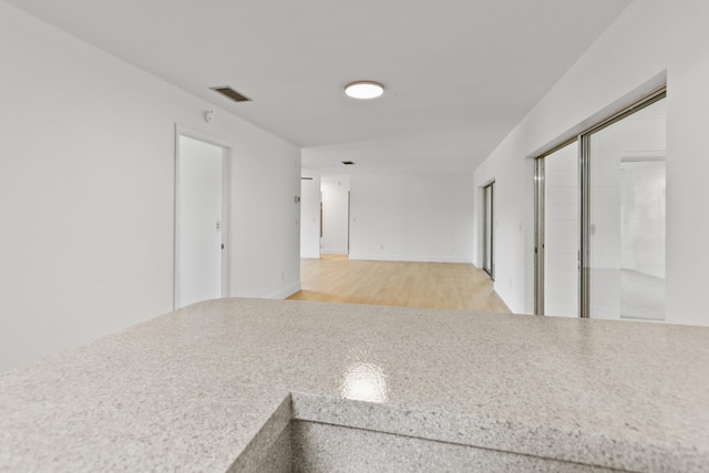 empty room featuring light wood finished floors, baseboards, and visible vents