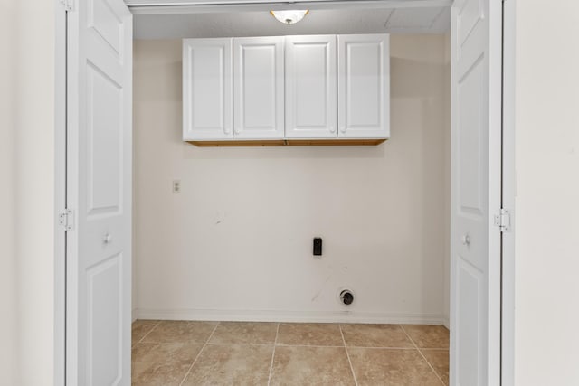 washroom with light tile patterned flooring, cabinet space, electric dryer hookup, and baseboards