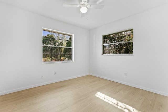 spare room with wood finished floors, a ceiling fan, and baseboards