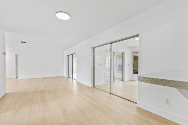 unfurnished room featuring baseboards, visible vents, and light wood finished floors