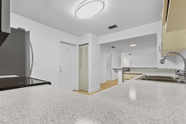 kitchen featuring a sink, visible vents, baseboards, light countertops, and freestanding refrigerator