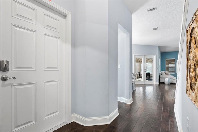 hall with dark wood-type flooring and a textured ceiling