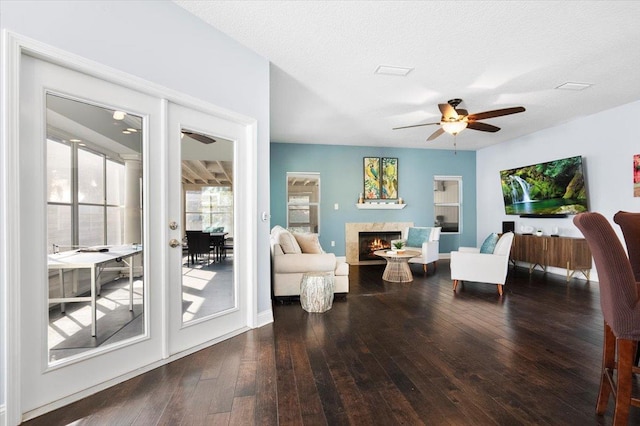 living room with dark wood-type flooring, a fireplace, a textured ceiling, and ceiling fan