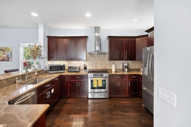 kitchen featuring sink, backsplash, stainless steel appliances, dark wood-type flooring, and wall chimney exhaust hood