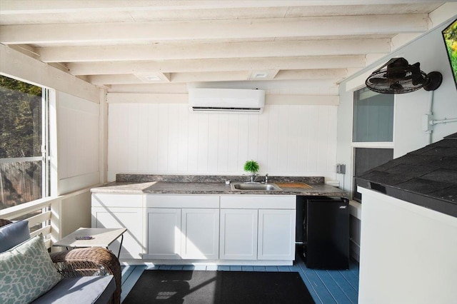 kitchen with sink, white cabinetry, a wall mounted AC, fridge, and beam ceiling