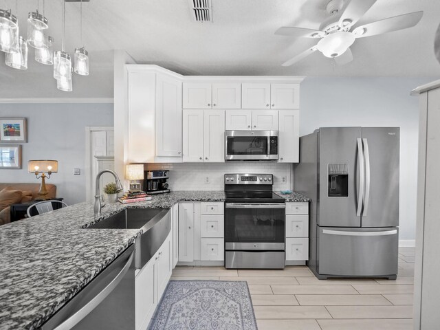 84 Seascape Cir, Saint Augustine, FL 32080 - kitchen featuring stainless steel appliances, a sink, dark stone counters, tasteful backsplash, and white cabinetry