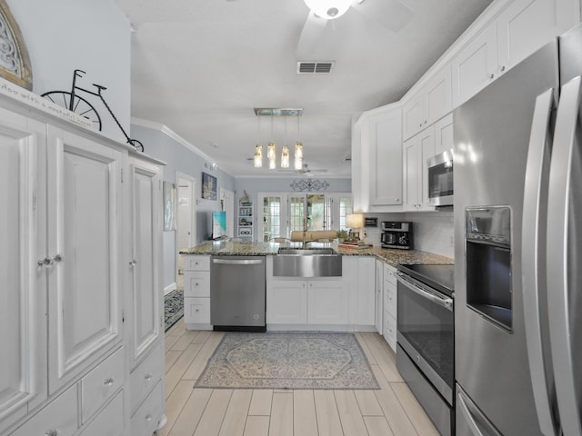 84 Seascape Cir, Saint Augustine, FL 32080 - kitchen featuring stainless steel appliances, ornamental molding, white cabinets, ceiling fan, and a peninsula