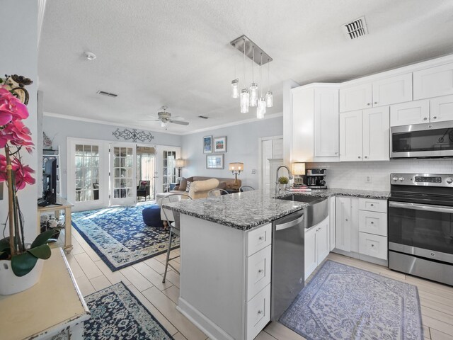 84 Seascape Cir, Saint Augustine, FL 32080 - kitchen with appliances with stainless steel finishes, a sink, crown molding, a peninsula, and white cabinets