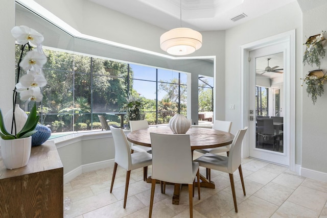 dining space with light tile patterned floors, ornamental molding, and a raised ceiling