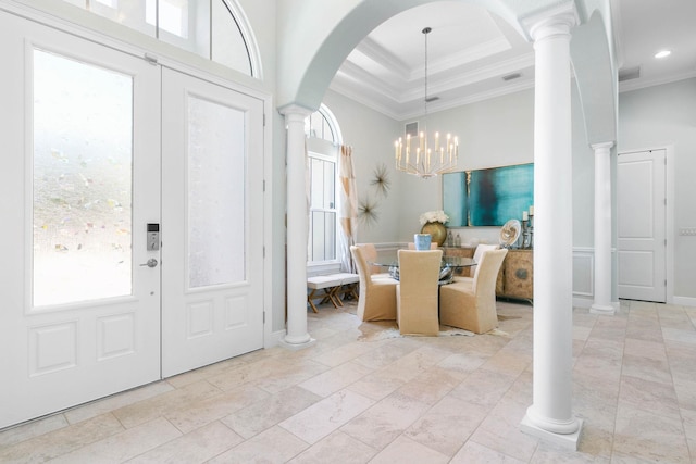 foyer with decorative columns, crown molding, an inviting chandelier, and a tray ceiling