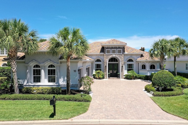 mediterranean / spanish-style house featuring a front yard and french doors