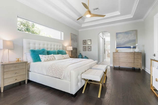 bedroom featuring dark wood-type flooring, ensuite bathroom, crown molding, a raised ceiling, and ceiling fan