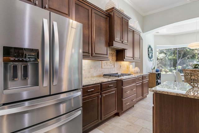 kitchen featuring dark brown cabinetry, light stone counters, appliances with stainless steel finishes, ornamental molding, and backsplash