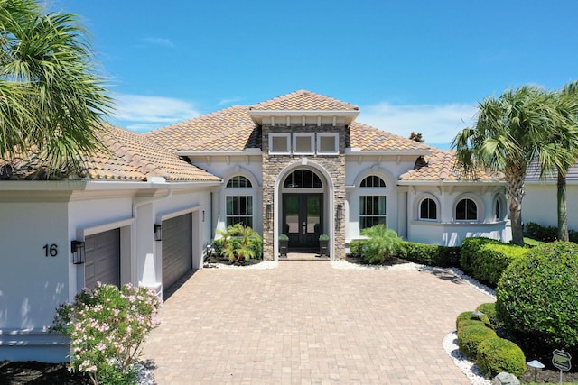 mediterranean / spanish home with a garage and french doors