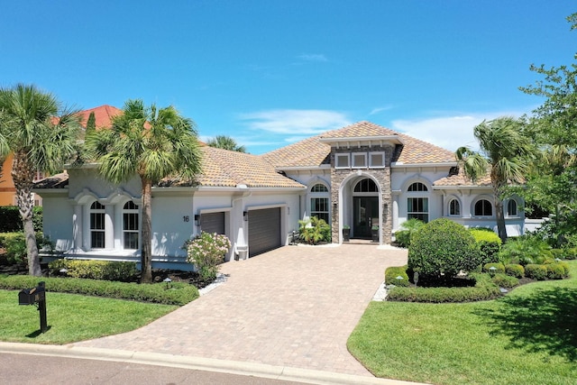 16 Hammock Beach Pkwy, Palm Coast, FL 32137 - mediterranean / spanish-style home featuring an attached garage, driveway, stucco siding, a front lawn, and stone siding