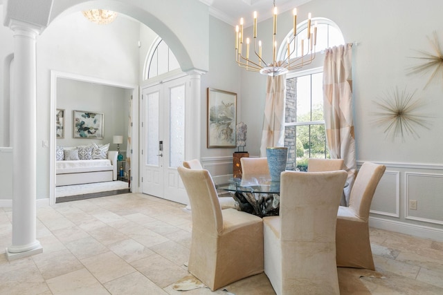 dining room featuring decorative columns, crown molding, and an inviting chandelier