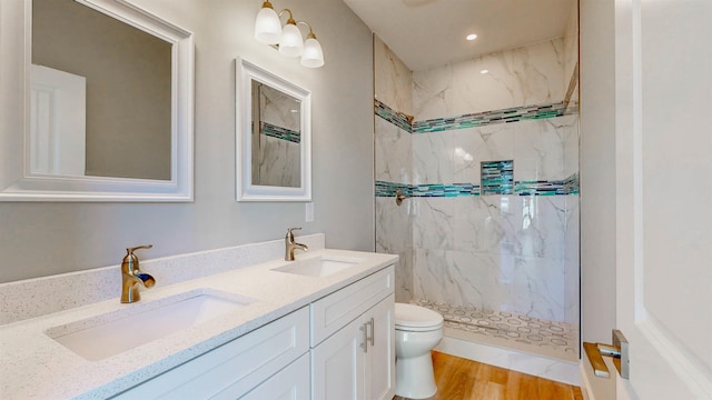 bathroom featuring vanity, hardwood / wood-style flooring, toilet, and tiled shower