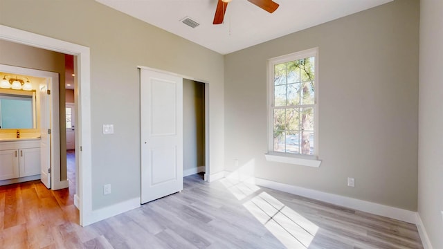 unfurnished bedroom featuring ensuite bathroom, light wood-type flooring, sink, and ceiling fan