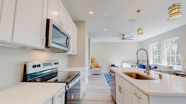 kitchen featuring pendant lighting, white cabinetry, light stone countertops, and appliances with stainless steel finishes