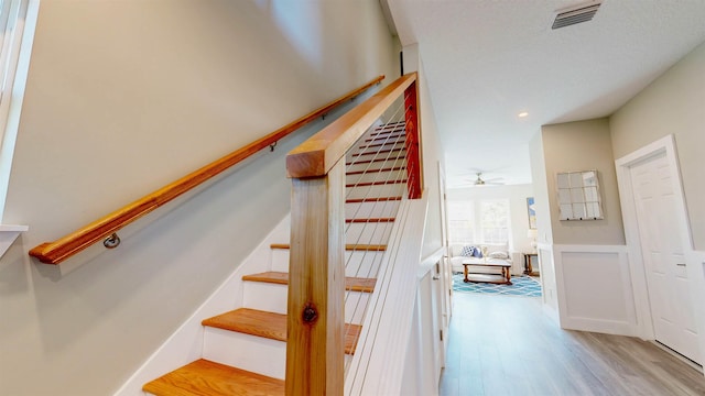 stairway with ceiling fan and hardwood / wood-style floors