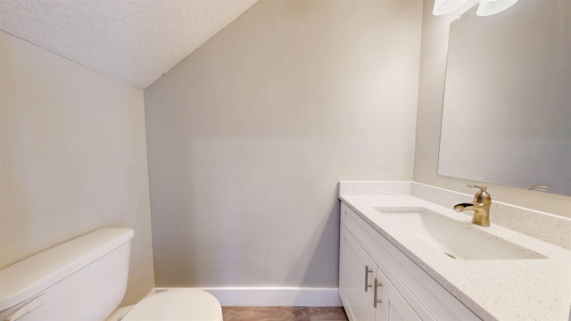 bathroom featuring vanity, a textured ceiling, and toilet