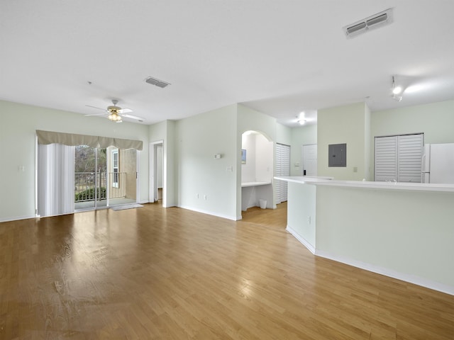 unfurnished living room featuring electric panel, ceiling fan, and light wood-type flooring