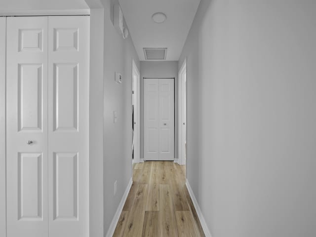 hallway featuring light wood-type flooring, visible vents, and baseboards