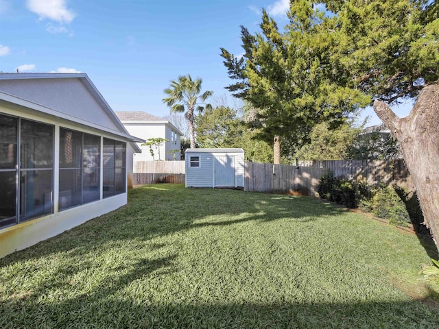 view of yard with an outbuilding, a shed, a fenced backyard, and a sunroom