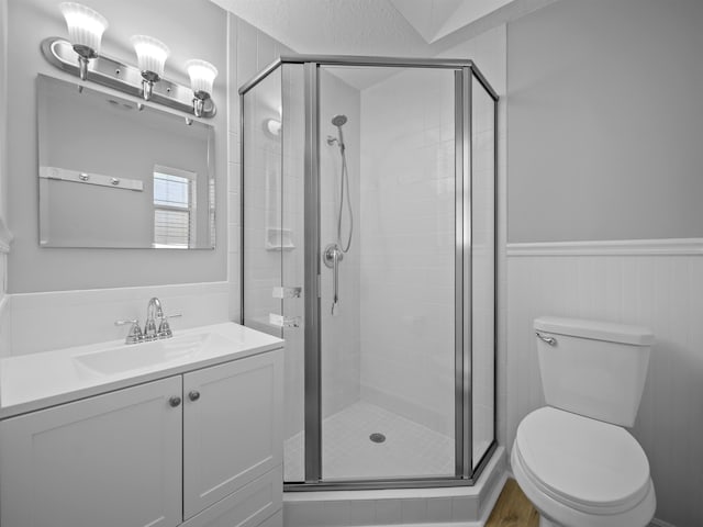 full bath with a wainscoted wall, vanity, a shower stall, and toilet