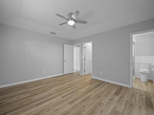 unfurnished bedroom with baseboards, ensuite bath, visible vents, and light wood-style floors