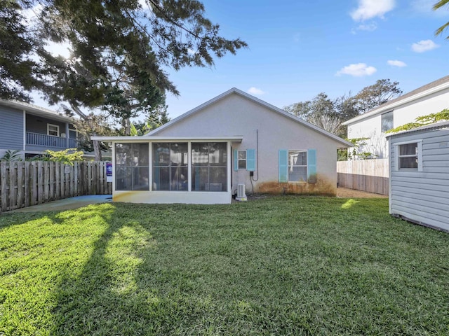 back of house with a sunroom, fence, a lawn, and stucco siding