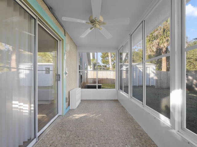 unfurnished sunroom featuring plenty of natural light, radiator heating unit, and ceiling fan