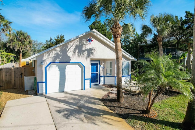 view of front of property featuring concrete driveway, fence, an attached garage, and stucco siding