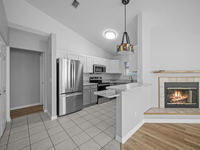 kitchen with a peninsula, a fireplace, visible vents, white cabinets, and appliances with stainless steel finishes