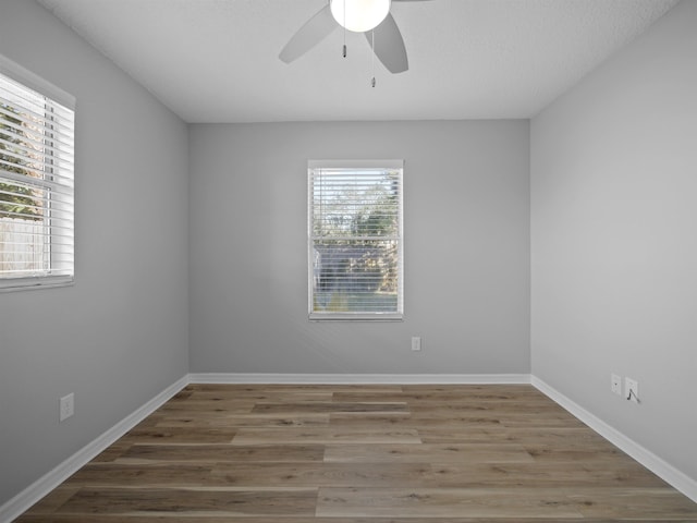 unfurnished room with ceiling fan, wood finished floors, and baseboards