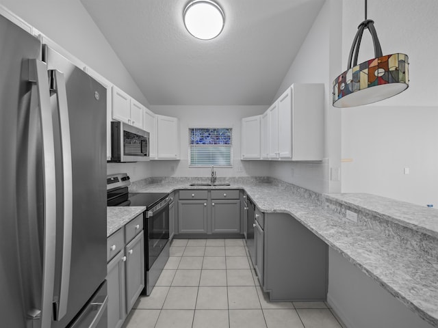 kitchen with lofted ceiling, light tile patterned floors, stainless steel appliances, a sink, and gray cabinets