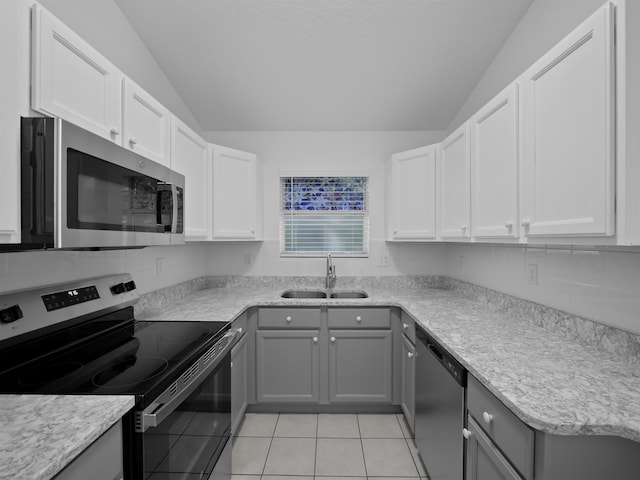 kitchen with vaulted ceiling, stainless steel appliances, a sink, and gray cabinetry