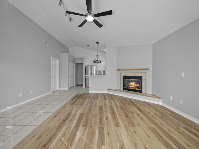 unfurnished living room with light wood-type flooring, a tile fireplace, visible vents, and ceiling fan