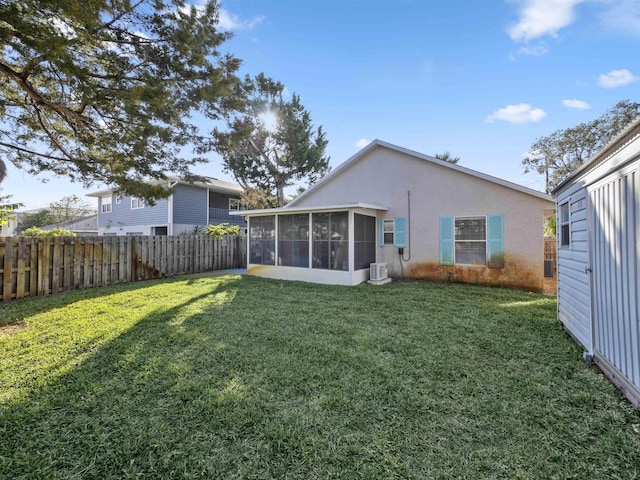 rear view of property with a yard, fence private yard, a sunroom, and stucco siding