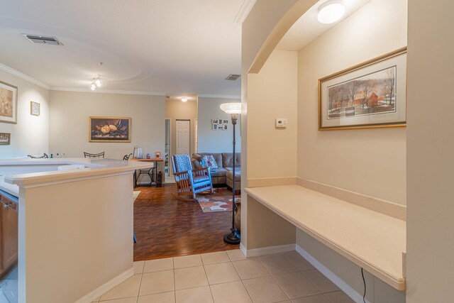 hall featuring light tile patterned floors and crown molding