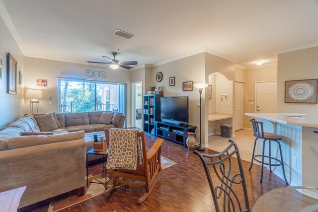 living room featuring ceiling fan, ornamental molding, and wood-type flooring