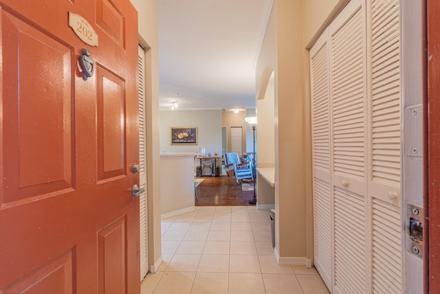 corridor with ornamental molding and light tile patterned floors